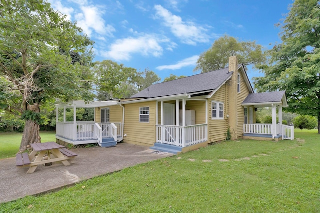 rear view of property with a lawn and covered porch