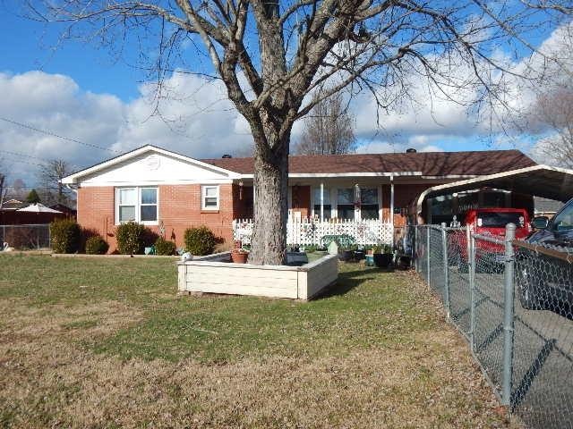 ranch-style home featuring a carport and a front lawn