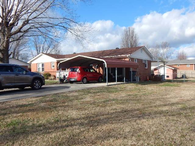 view of parking / parking lot featuring a yard and a carport