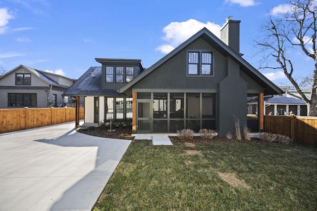 rear view of house featuring a lawn and a sunroom