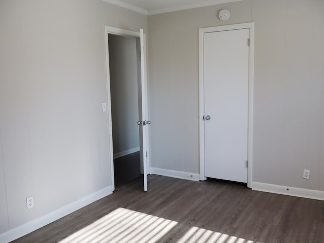 unfurnished bedroom with dark wood-type flooring and ornamental molding