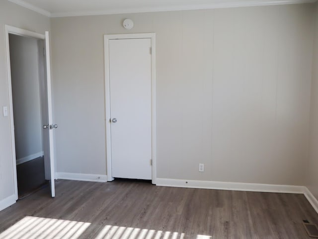 unfurnished bedroom with dark hardwood / wood-style flooring and crown molding