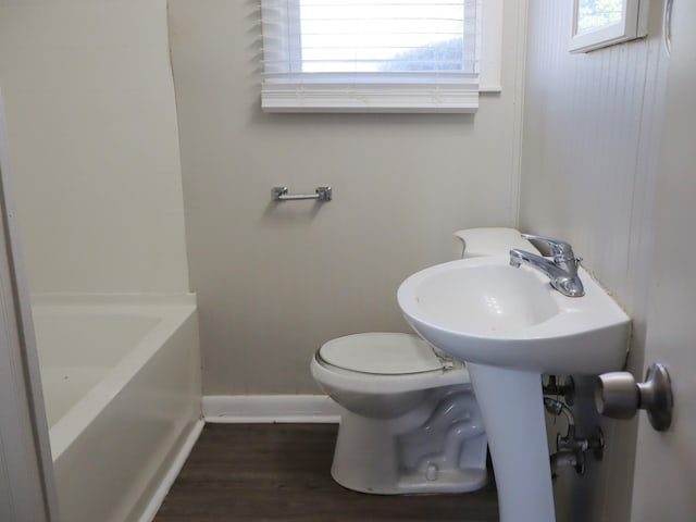 bathroom featuring a tub, wood-type flooring, and toilet