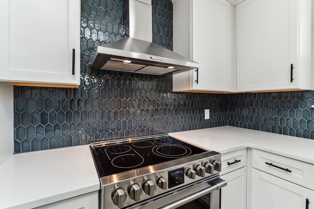 kitchen featuring white cabinets, wall chimney range hood, backsplash, and stainless steel range