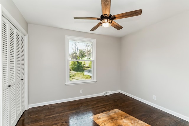 unfurnished bedroom with dark hardwood / wood-style flooring, ceiling fan, and a closet