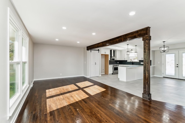 unfurnished living room with french doors, hardwood / wood-style flooring, a healthy amount of sunlight, and beam ceiling