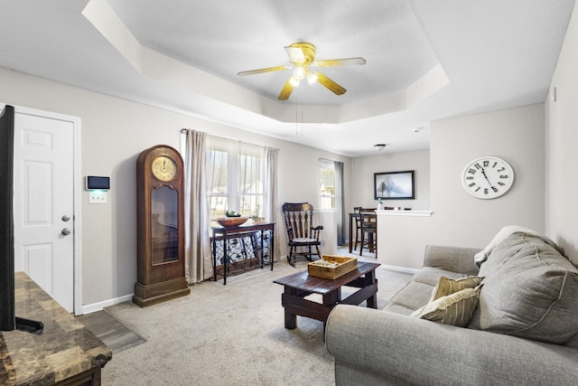 living room with ceiling fan, light carpet, and a tray ceiling