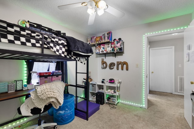 bedroom featuring ceiling fan, light colored carpet, and a textured ceiling