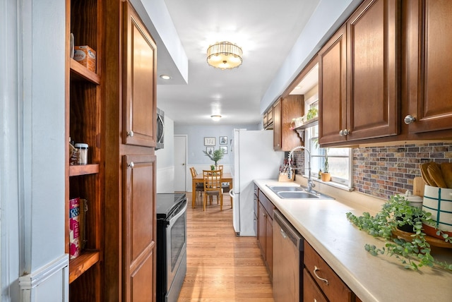 kitchen featuring decorative backsplash, sink, light wood-type flooring, and appliances with stainless steel finishes