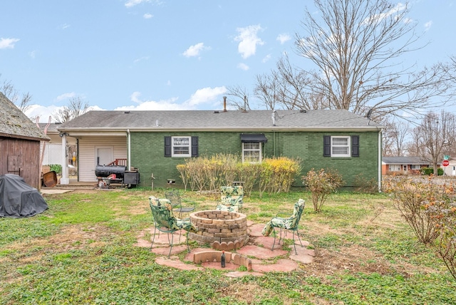 rear view of house featuring a fire pit and a yard