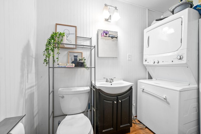 bathroom with toilet, vanity, stacked washer and clothes dryer, and parquet flooring