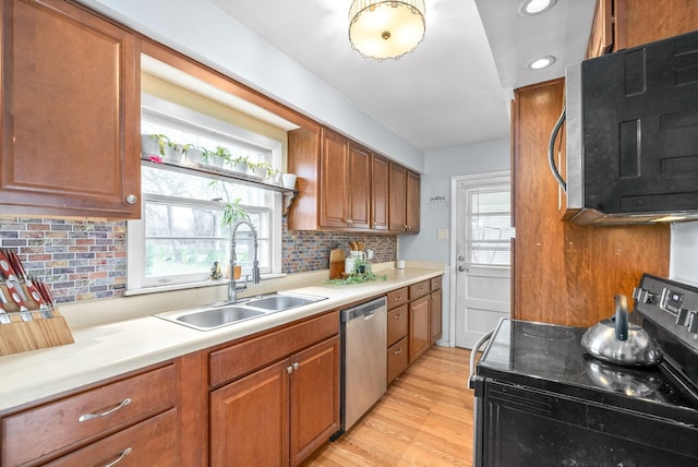 kitchen with decorative backsplash, a wealth of natural light, stainless steel appliances, sink, and light hardwood / wood-style flooring