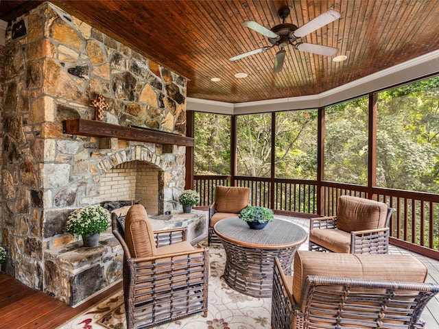 sunroom featuring a stone fireplace, ceiling fan, and wood ceiling