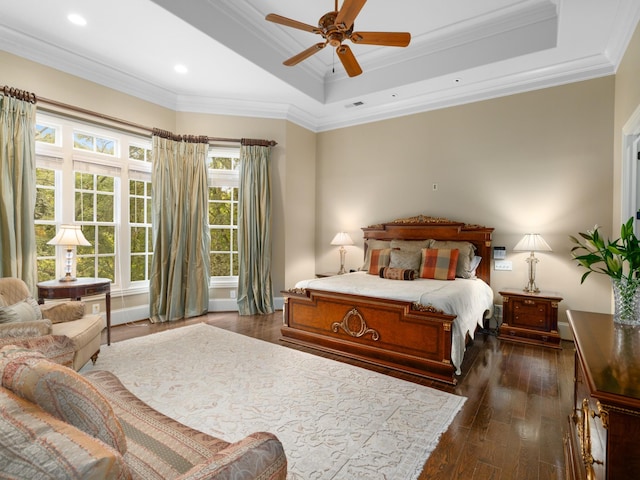 bedroom with ceiling fan, dark hardwood / wood-style floors, crown molding, and a tray ceiling