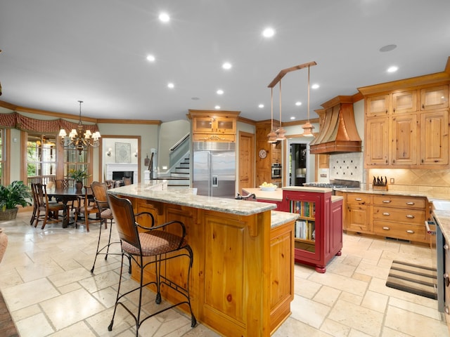 kitchen featuring custom range hood, crown molding, decorative light fixtures, a center island, and built in fridge