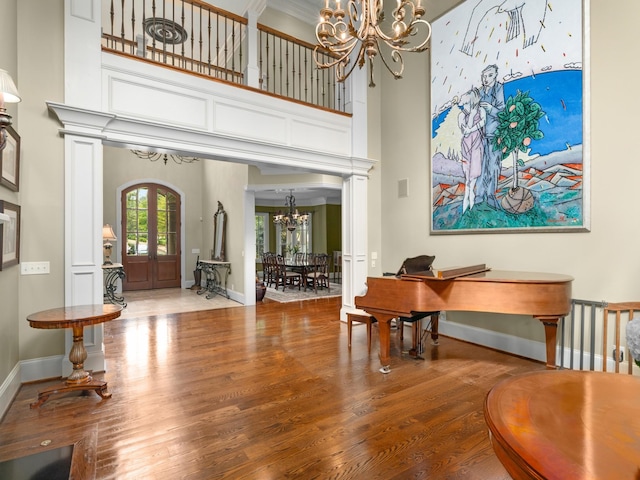 entrance foyer with hardwood / wood-style floors, a notable chandelier, a high ceiling, and french doors