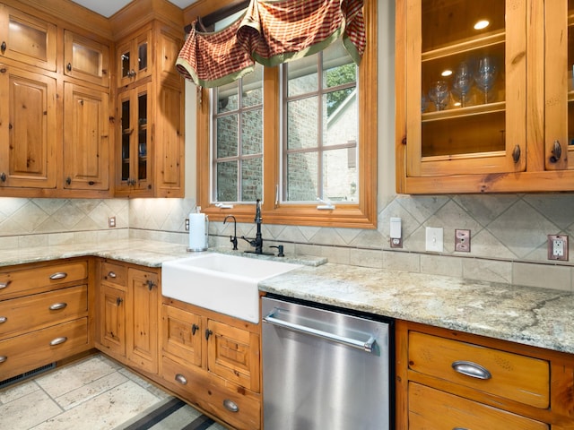 kitchen with decorative backsplash, light stone counters, sink, and stainless steel dishwasher