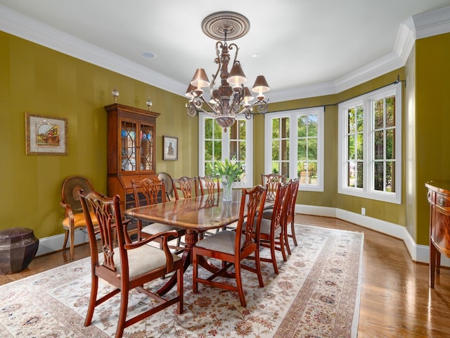 dining room with wood-type flooring, an inviting chandelier, and ornamental molding