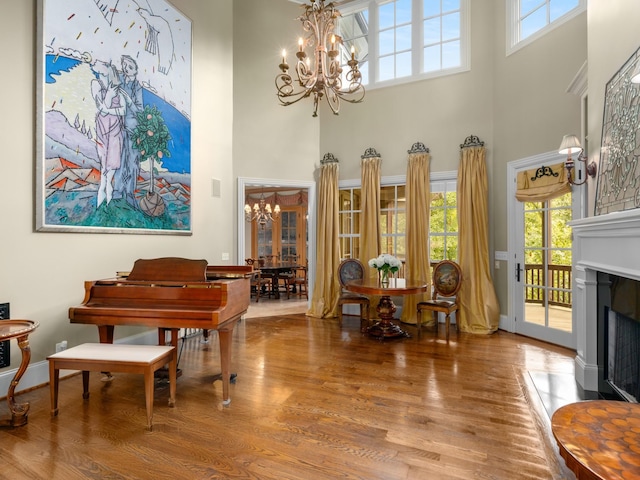 misc room with wood-type flooring, a towering ceiling, and an inviting chandelier