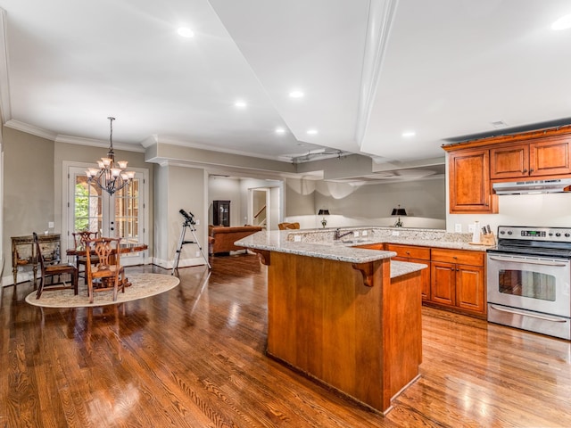 kitchen with stainless steel electric range oven, hanging light fixtures, light stone counters, a notable chandelier, and a kitchen bar