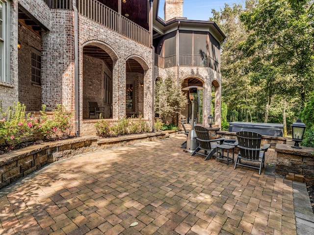 view of patio / terrace featuring a balcony, a hot tub, and a sunroom