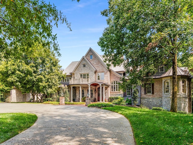 view of front of house featuring covered porch, a balcony, and a front yard