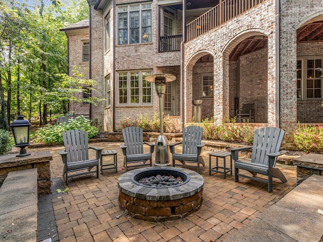 view of patio with a fire pit and a balcony