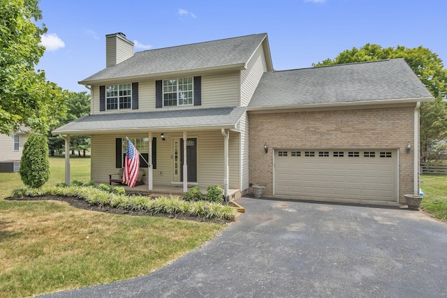 view of front of property with covered porch, a garage, and a front yard