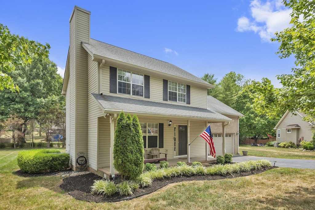 view of front of property featuring a front lawn, a porch, and a garage