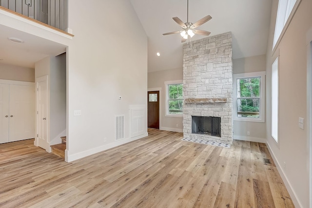 unfurnished living room featuring ceiling fan, a fireplace, high vaulted ceiling, and light hardwood / wood-style floors