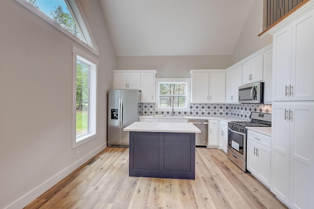 kitchen with a center island, stainless steel appliances, tasteful backsplash, light hardwood / wood-style flooring, and white cabinets