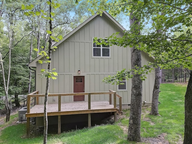 rear view of property featuring central AC unit, a lawn, and a wooden deck