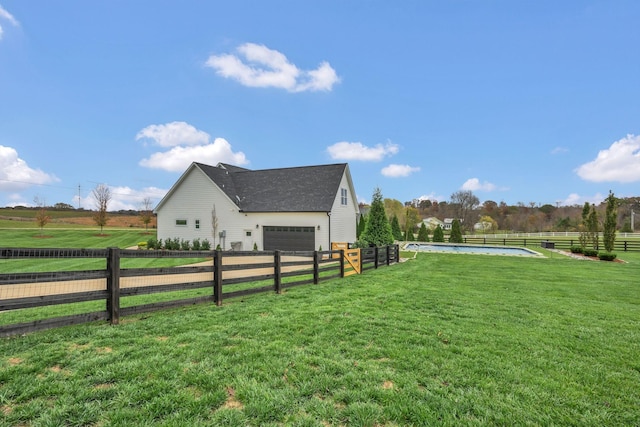 view of side of property featuring a yard, a rural view, and a garage