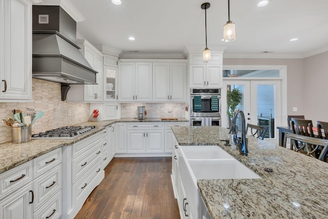 kitchen with white cabinetry, sink, pendant lighting, appliances with stainless steel finishes, and custom exhaust hood