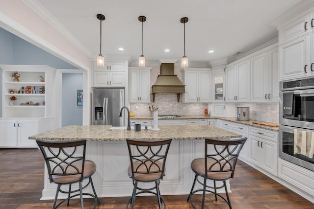 kitchen with a kitchen bar, premium range hood, stainless steel appliances, and an island with sink