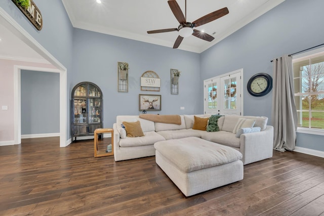 living room featuring ceiling fan, crown molding, a towering ceiling, and dark wood-type flooring