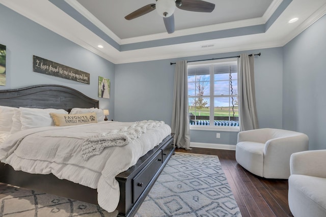 bedroom featuring dark hardwood / wood-style floors, a raised ceiling, ceiling fan, and ornamental molding