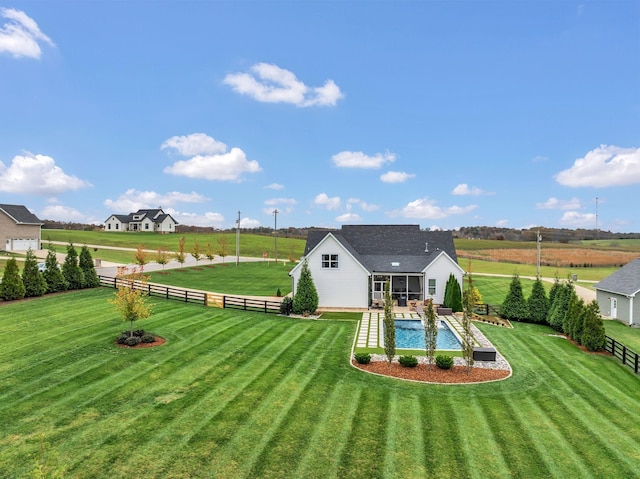 rear view of house with a lawn, a sunroom, and a fenced in pool