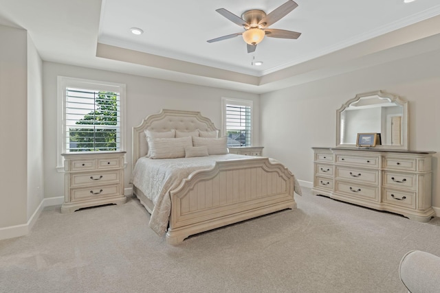 bedroom featuring a raised ceiling, ceiling fan, and light carpet