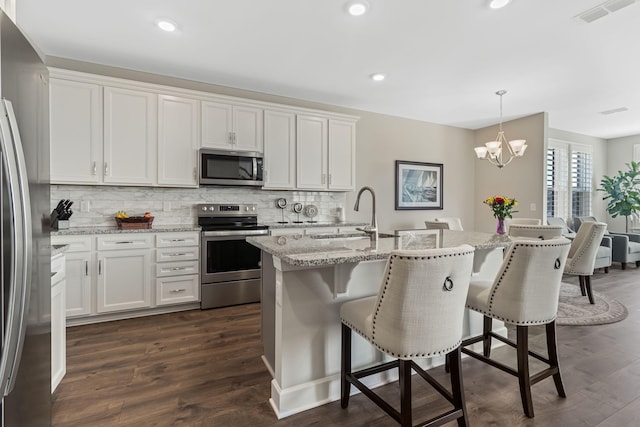 kitchen with white cabinetry, sink, backsplash, pendant lighting, and appliances with stainless steel finishes