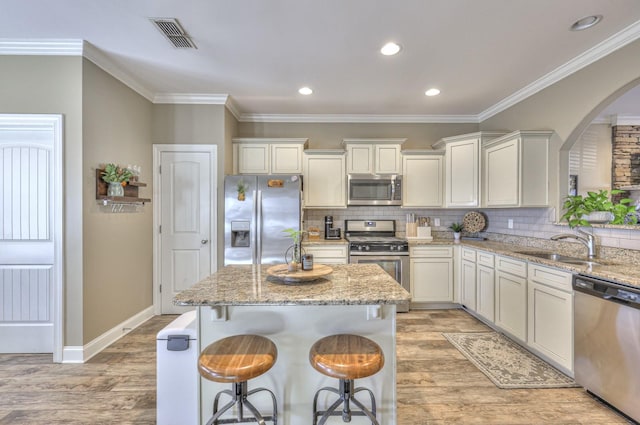 kitchen with a center island, light stone countertops, sink, and appliances with stainless steel finishes