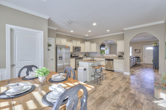 dining space featuring sink, light hardwood / wood-style floors, and ornamental molding