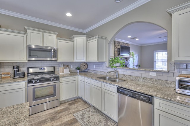 kitchen featuring appliances with stainless steel finishes, crown molding, sink, light hardwood / wood-style flooring, and white cabinets