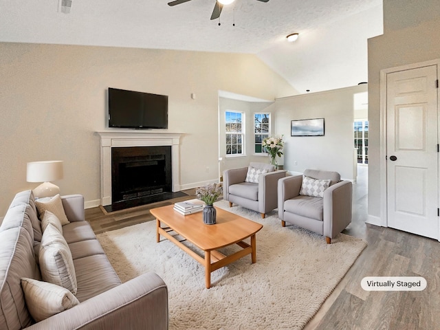 living room with hardwood / wood-style floors, a textured ceiling, vaulted ceiling, and ceiling fan