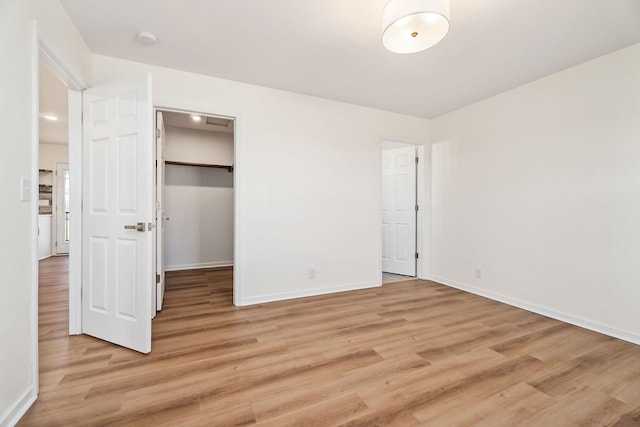 unfurnished bedroom featuring hardwood / wood-style floors, a walk in closet, and a closet