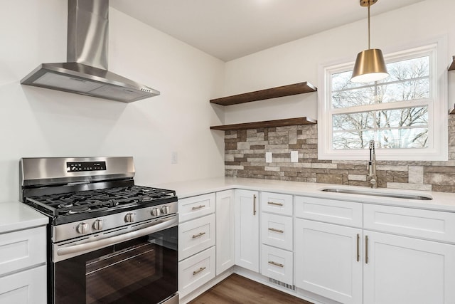 kitchen featuring white cabinets, wall chimney exhaust hood, sink, and gas range