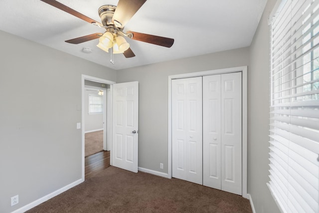 unfurnished bedroom featuring a closet, dark carpet, and ceiling fan