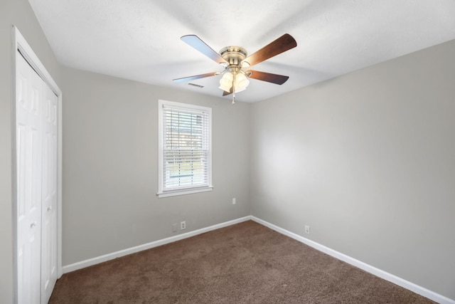 unfurnished bedroom featuring a closet, dark carpet, and ceiling fan