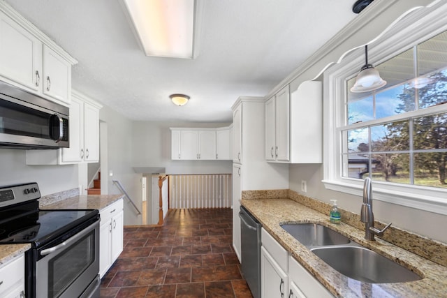 kitchen with white cabinets, appliances with stainless steel finishes, pendant lighting, and sink