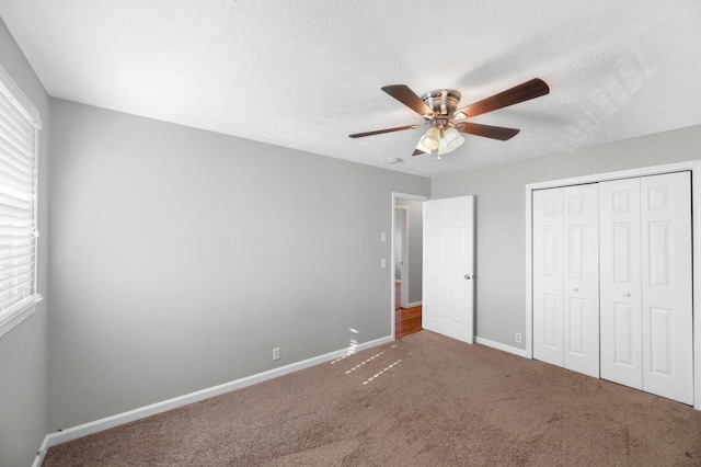 unfurnished bedroom featuring carpet, a textured ceiling, a closet, and ceiling fan